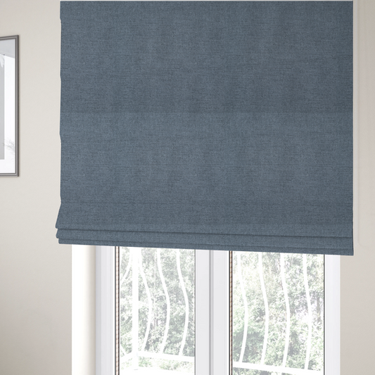 The fabric used to create these Roman blinds is a finely textured weave in a soft denim, slate blue, or pigeon blue shade. The material features a subtle heathered look with finely blended threads of muted blue and cool grey undertones throughout.