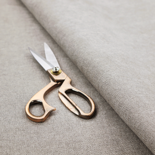 A finely textured weave in a light greige, taupe, or soft pebble grey shade. The material features a subtle heathered look with finely blended threads of cool grey and warm beige undertones throughout.