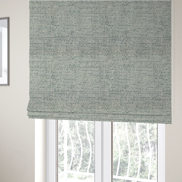The fabric used to create these Roman blinds is a material features a dense, multi-toned weave with a light cream or off-white background, intricately interlaced with horizontal flecks of teal, mint green, and soft grey threads throughout.