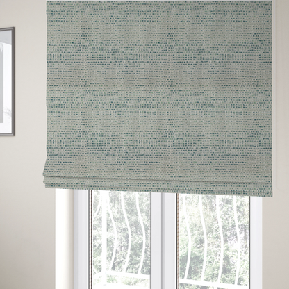 The fabric used to create these Roman blinds is a material features a dense, multi-toned weave with a light cream or off-white background, intricately interlaced with horizontal flecks of teal, mint green, and soft grey threads throughout.