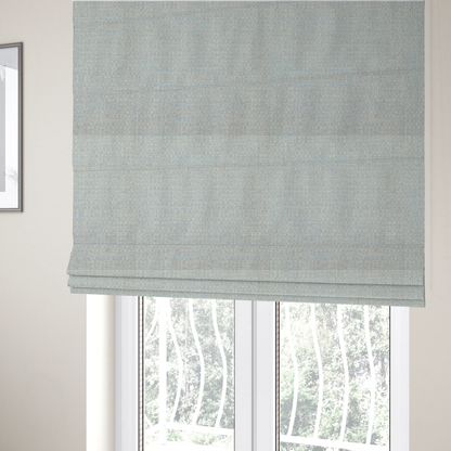 The fabric used to create these Roman blinds is a material features a dense, light-toned weave with a pale cream and off-white base, subtly interlaced with delicate horizontal flecks of soft baby blue and light grey threads throughout.