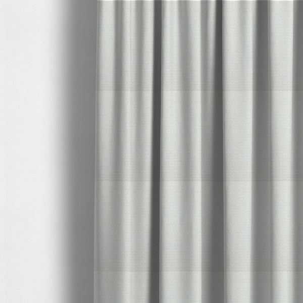 The fabric used to create these made-to-measure curtains is a material features a dense, minimalist weave in a uniform bright cream or off-white colour, highlighting the subtle horizontal texture of the interlaced threads.