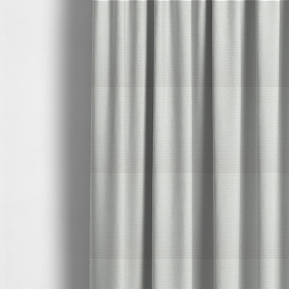 The fabric used to create these made-to-measure curtains is a material features a dense, minimalist weave in a uniform bright cream or off-white colour, highlighting the subtle horizontal texture of the interlaced threads.