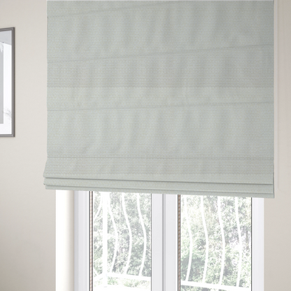 The fabric used to create these Roman blinds is a material features a dense, minimalist weave in a uniform bright cream or off-white colour, highlighting the subtle horizontal texture of the interlaced threads.