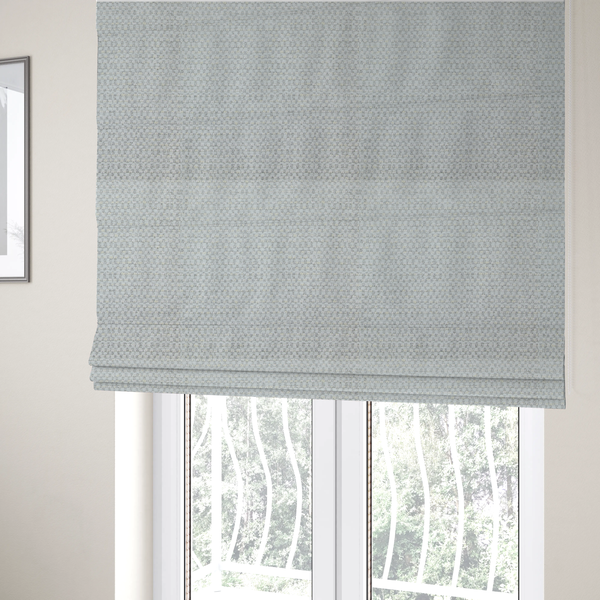 The fabric used to create these Roman blinds is a material features a dense, multi-toned neutral weave with a pale grey and silver-toned base, intricately interlaced with horizontal flecks of soft cream and off-white threads throughout.