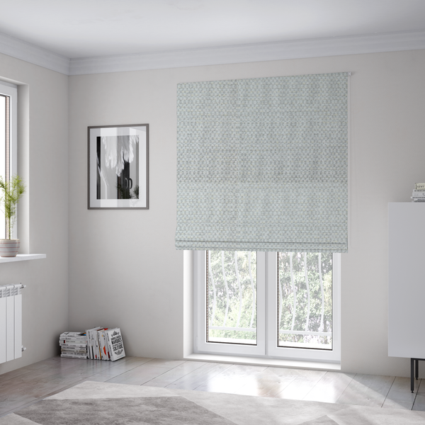 The fabric used to create these Roman blinds is a material features a dense, multi-toned neutral weave with a pale grey and silver-toned base, intricately interlaced with horizontal flecks of soft cream and off-white threads throughout.