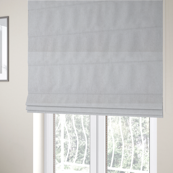 The fabric used to create these Roman blinds is a light grey or off-white woven fabric with a fine, textured basket weave pattern.