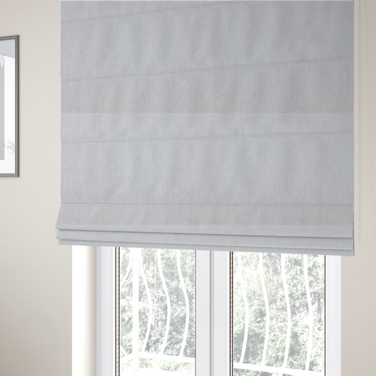 The fabric used to create these Roman blinds is a light grey or off-white woven fabric with a fine, textured basket weave pattern.