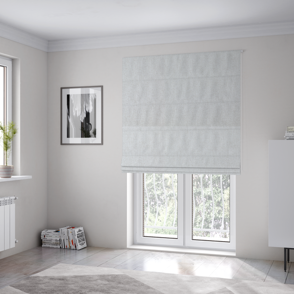 The fabric used to create these Roman blinds is a light grey or off-white woven fabric with a fine, textured basket weave pattern.