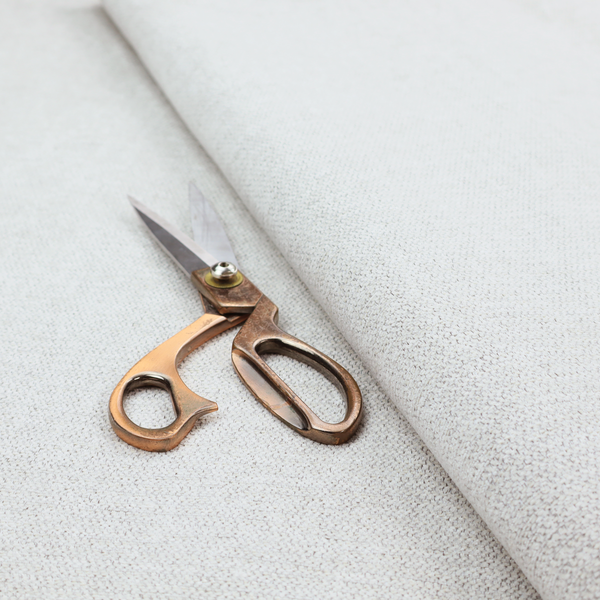A lightly textured upholstery fabric in a pale cream or light grey. The material features a fine, tight weave with faint horizontal striations and a matte finish.