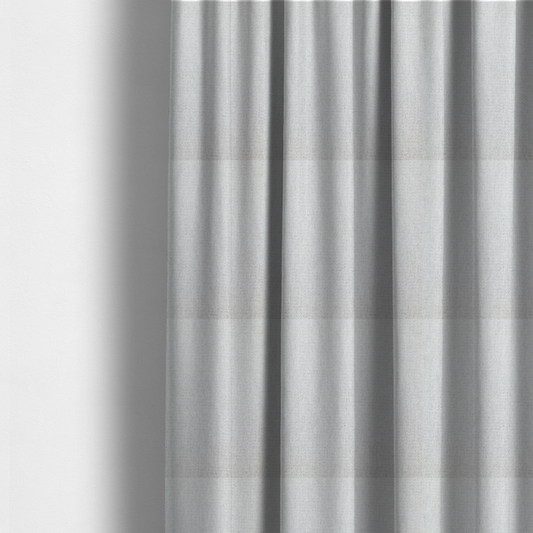 The fabric used to create these made-to-measure curtains is a lightly textured upholstery fabric in a pale cream or light grey. The material features a fine, tight weave with faint horizontal striations and a matte finish.