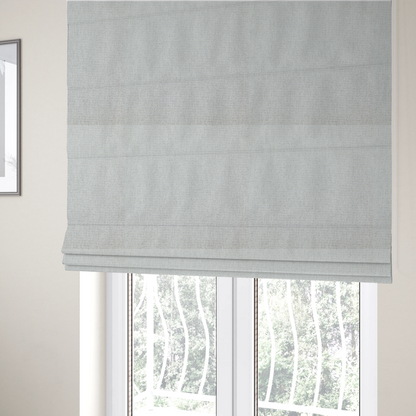 The fabric used to create these Roman blinds is a lightly textured upholstery fabric in a pale cream or light grey. The material features a fine, tight weave with faint horizontal striations and a matte finish.