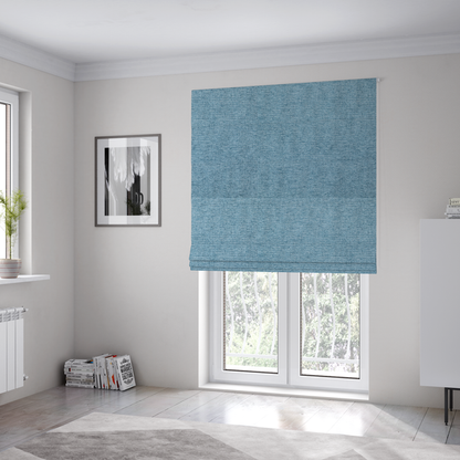 The fabric used to create these Roman blinds is a soft blue woven fabric with a fine, heathered texture.