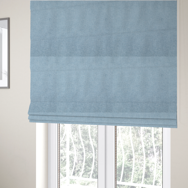 The fabric used to create these Roman blinds is a pale powder blue woven fabric with a fine, heathered texture.