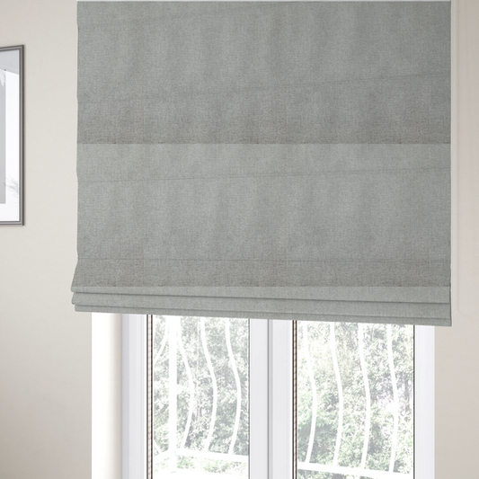 The fabric used to create these Roman blinds is a light silver-grey woven fabric with a fine, heathered texture.