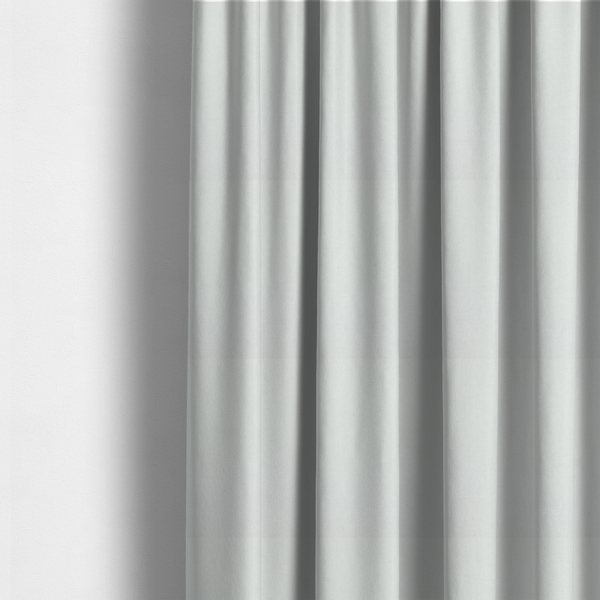 The fabric used to create these made-to-measure curtains is a solid, off-white or light cream-coloured woven fabric. The weave appears consistent and fine, creating a subtle, clean aesthetic.