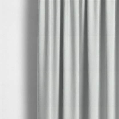 The fabric used to create these made-to-measure curtains is a solid, off-white or light cream-coloured woven fabric. The weave appears consistent and fine, creating a subtle, clean aesthetic.