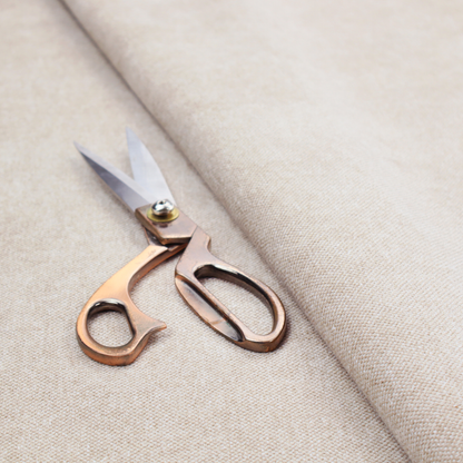 A woven upholstery fabric in a warm, light beige or sand colour, featuring a consistent, textured surface pattern.