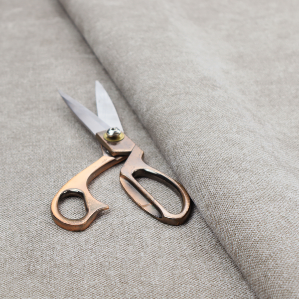 A woven upholstery fabric in a neutral, soft grey tone, featuring a consistent and textured surface pattern.