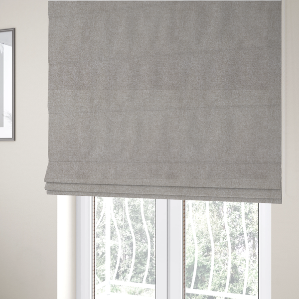 The fabric used to create these Roman blinds is a woven upholstery fabric in a neutral, soft grey tone, featuring a consistent and textured surface pattern.