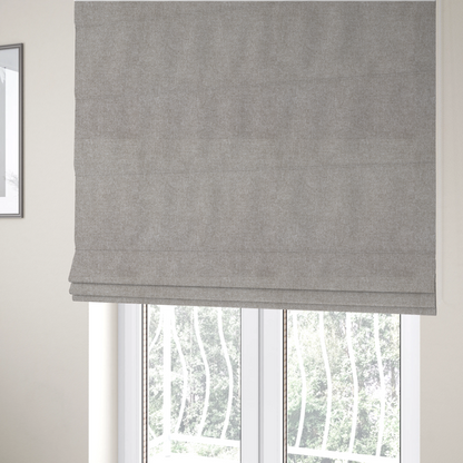 The fabric used to create these Roman blinds is a woven upholstery fabric in a neutral, soft grey tone, featuring a consistent and textured surface pattern.