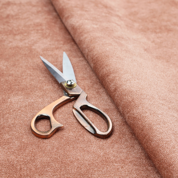 A fine, woven upholstery fabric in a warm, muted terracotta or copper tone, featuring a consistent and textured surface pattern.