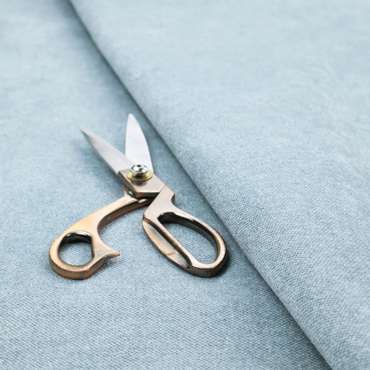 A fine, woven upholstery fabric in a soft, airy, powder blue tone, featuring a consistent and textured surface pattern.