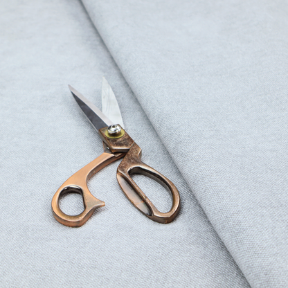 A fine, woven upholstery fabric in a subtle, cool-toned pale grey or off-white, featuring a consistent and textured surface pattern.