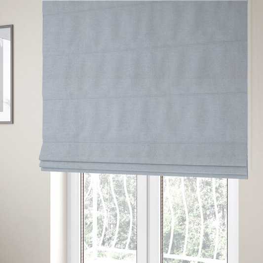 The fabric used to create these Roman blinds is a fine, woven upholstery fabric in a subtle, cool-toned pale grey or off-white, featuring a consistent and textured surface pattern.