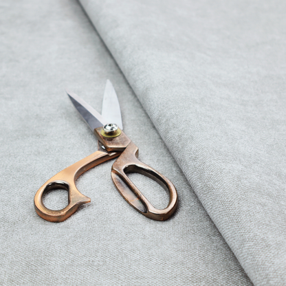 A fine, woven upholstery fabric in a clean, neutral light grey or soft silver tone, featuring a consistent and textured surface pattern.