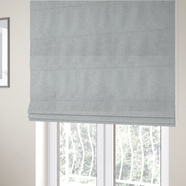 The fabric used to create these Roman blinds is a fine, woven upholstery fabric in a clean, neutral light grey or soft silver tone, featuring a consistent and textured surface pattern.