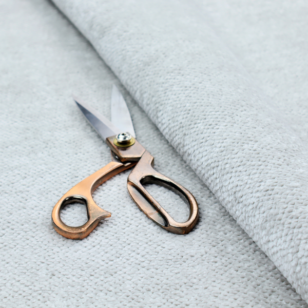 A cool-toned, light grey or silver upholstery fabric. It showcases the same dense, uniform, boucle-style weave seen in the previous image, consisting of small, looped, and nubby yarn fibres that create a soft, tactile surface.