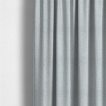 The fabric used to create these made-to-measure curtains is a cool-toned, light grey or silver upholstery fabric. It showcases the same dense, uniform, boucle-style weave seen in the previous image, consisting of small, looped, and nubby yarn fibres that create a soft, tactile surface.