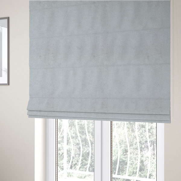 The fabric used to create these Roman blinds is a cool-toned, light grey or silver upholstery fabric. It showcases the same dense, uniform, boucle-style weave seen in the previous image, consisting of small, looped, and nubby yarn fibres that create a soft, tactile surface.