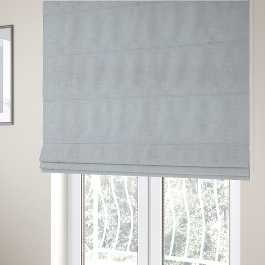 The fabric used to create these Roman blinds is a cool-toned, light grey or silver upholstery fabric. It showcases the same dense, uniform, boucle-style weave seen in the previous image, consisting of small, looped, and nubby yarn fibres that create a soft, tactile surface.