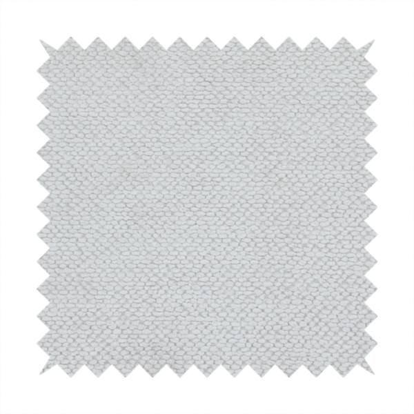 A light, neutral-toned upholstery fabric. It features the same signature dense, uniform, boucle-style weave as the previous samples, composed of small, looped, and nubby yarn fibres that provide a soft, tactile, and inviting surface.