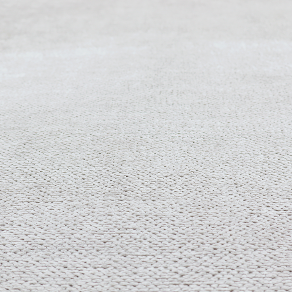 A light, neutral-toned upholstery fabric. It features the same signature dense, uniform, boucle-style weave as the previous samples, composed of small, looped, and nubby yarn fibres that provide a soft, tactile, and inviting surface.