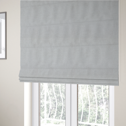 The fabric used to create these Roman blinds is a light, neutral-toned upholstery fabric. It features the same signature dense, uniform, boucle-style weave as the previous samples, composed of small, looped, and nubby yarn fibres that provide a soft, tactile, and inviting surface.