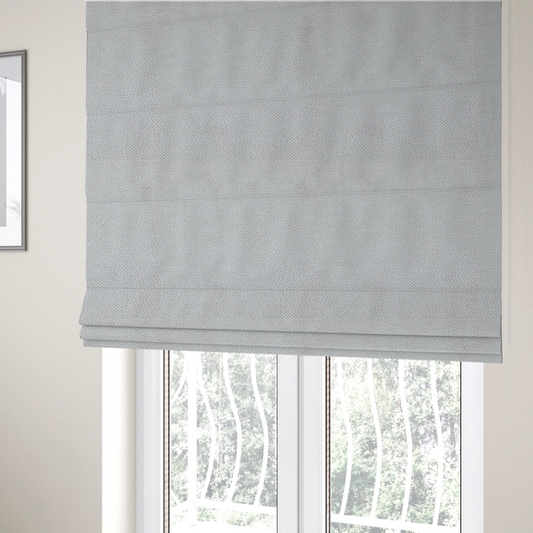 The fabric used to create these Roman blinds is a light, neutral-toned upholstery fabric. It features the same signature dense, uniform, boucle-style weave as the previous samples, composed of small, looped, and nubby yarn fibres that provide a soft, tactile, and inviting surface.