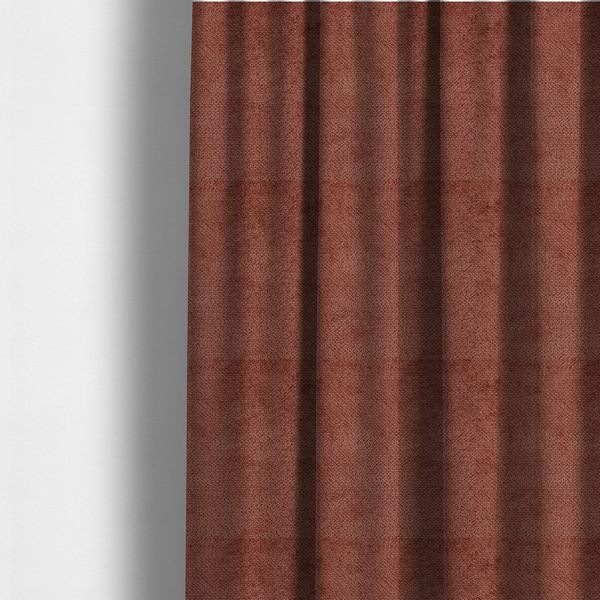 The fabric used to create these made-to-measure curtains is a rich, terracotta or rust-toned upholstery fabric. It maintains the signature dense, uniform, boucle-style weave featured in the collection, composed of small, looped, and nubby yarn fibres that provide a soft and tactile surface.