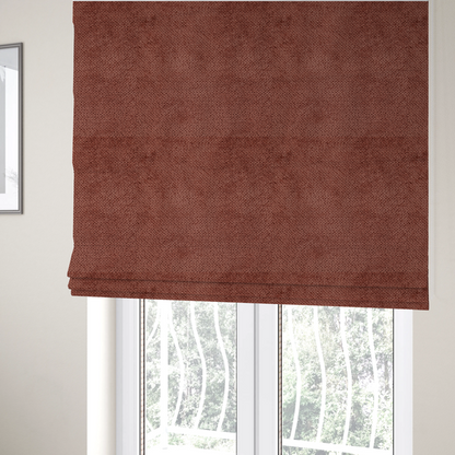 The fabric used to create these Roman blinds is a rich, terracotta or rust-toned upholstery fabric. It maintains the signature dense, uniform, boucle-style weave featured in the collection, composed of small, looped, and nubby yarn fibres that provide a soft and tactile surface.