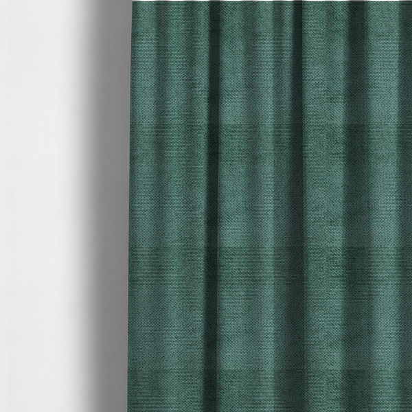 The fabric used to create these made-to-measure curtains is a deep, rich teal or blue-green upholstery fabric. It maintains the signature dense, uniform, boucle-style weave of the collection, composed of small, looped, and nubby yarn fibres that create a soft and tactile surface.