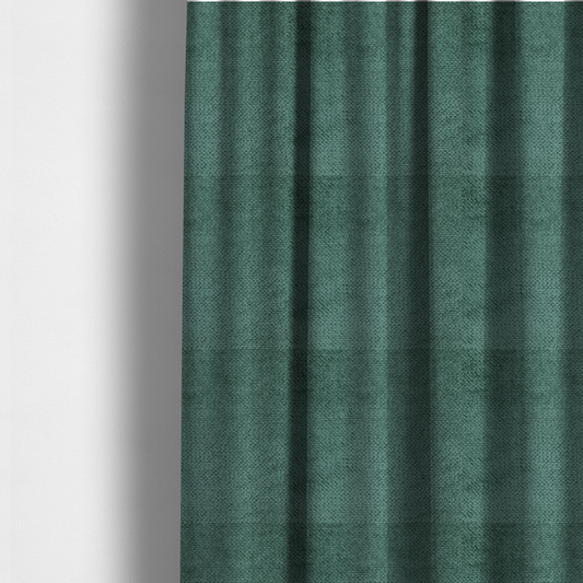 The fabric used to create these made-to-measure curtains is a deep, rich teal or blue-green upholstery fabric. It maintains the signature dense, uniform, boucle-style weave of the collection, composed of small, looped, and nubby yarn fibres that create a soft and tactile surface.