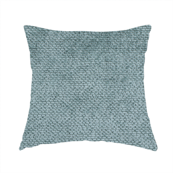 The fabric used to create this handmade cushion is a cool, muted blue or slate-toned upholstery fabric. It features the same signature dense, uniform, boucle-style weave as the previous samples, characterized by small, looped, and nubby yarn fibres that create a soft and tactile surface.