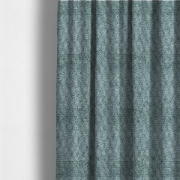 The fabric used to create these made-to-measure curtains is a cool, muted blue or slate-toned upholstery fabric. It features the same signature dense, uniform, boucle-style weave as the previous samples, characterized by small, looped, and nubby yarn fibres that create a soft and tactile surface.