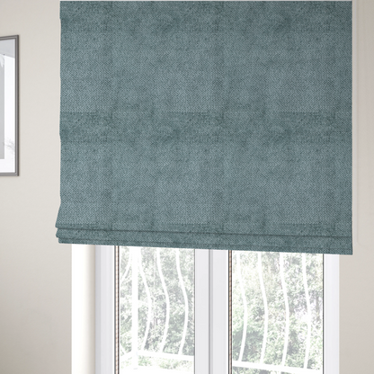 The fabric used to create these Roman blinds is a cool, muted blue or slate-toned upholstery fabric. It features the same signature dense, uniform, boucle-style weave as the previous samples, characterized by small, looped, and nubby yarn fibres that create a soft and tactile surface.