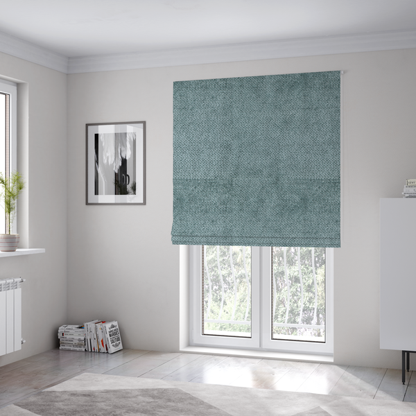 The fabric used to create these Roman blinds is a cool, muted blue or slate-toned upholstery fabric. It features the same signature dense, uniform, boucle-style weave as the previous samples, characterized by small, looped, and nubby yarn fibres that create a soft and tactile surface.