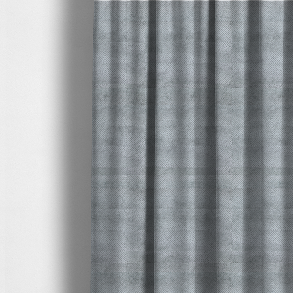 The fabric used to create these made-to-measure curtains is a soft, light-toned, cool-grey upholstery fabric. It features the signature dense, uniform, boucle-style weave of the collection, created with small, looped, and nubby yarn fibres that offer a comfortable, tactile surface.