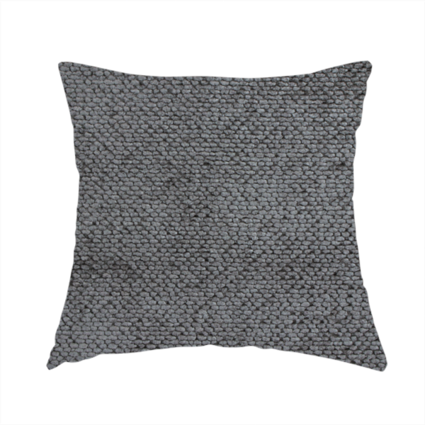 The fabric used to create this handmade cushion is a deep, dark grey or graphite-toned upholstery fabric. It features the signature dense, uniform, boucle-style weave of the collection, composed of small, looped, and nubby yarn fibres that create a soft and tactile surface.