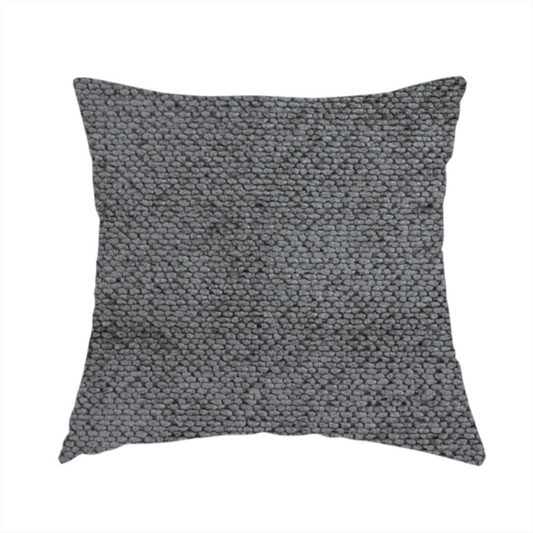 The fabric used to create this handmade cushion is a deep, dark grey or graphite-toned upholstery fabric. It features the signature dense, uniform, boucle-style weave of the collection, composed of small, looped, and nubby yarn fibres that create a soft and tactile surface.